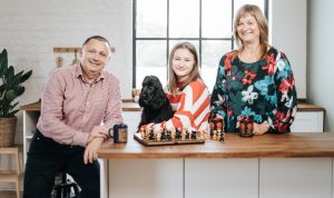 Family and cocker spaniel puppy playing chess